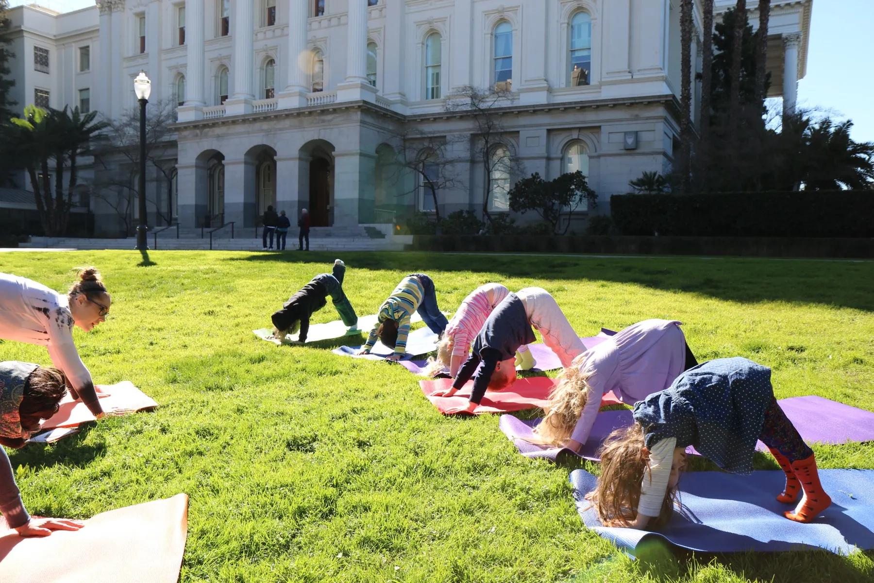 Preschoolers in an outdoor downward-dog yoga pose during a mindfulness-based learning session at Growing Mindfully Sacramento.